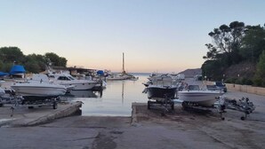 A marina with boats docked, a clear sky, and a calm sea.