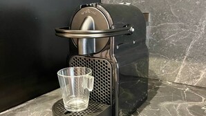 A Nespresso coffee machine with a clear glass cup on its drip tray.