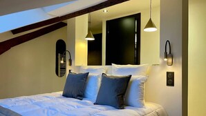 A bedroom with a bed, two wall-mounted lights, a window, and a door.