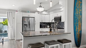 A modern kitchen with white cabinets, stainless steel appliances, and a marble countertop. - Jacks Blue Haven- 3/2 Heated Pool, Game Room & Close to Gulf Beaches!!  (Largo)