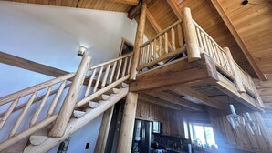 A wooden staircase with a handrail leading to a second-floor balcony.