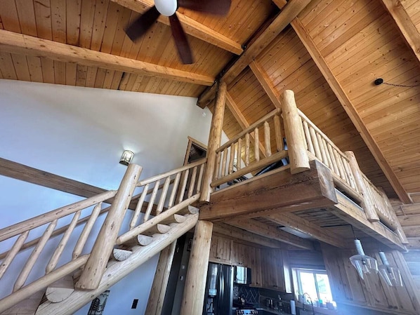 A wooden staircase with a handrail leading to a second-floor balcony.
