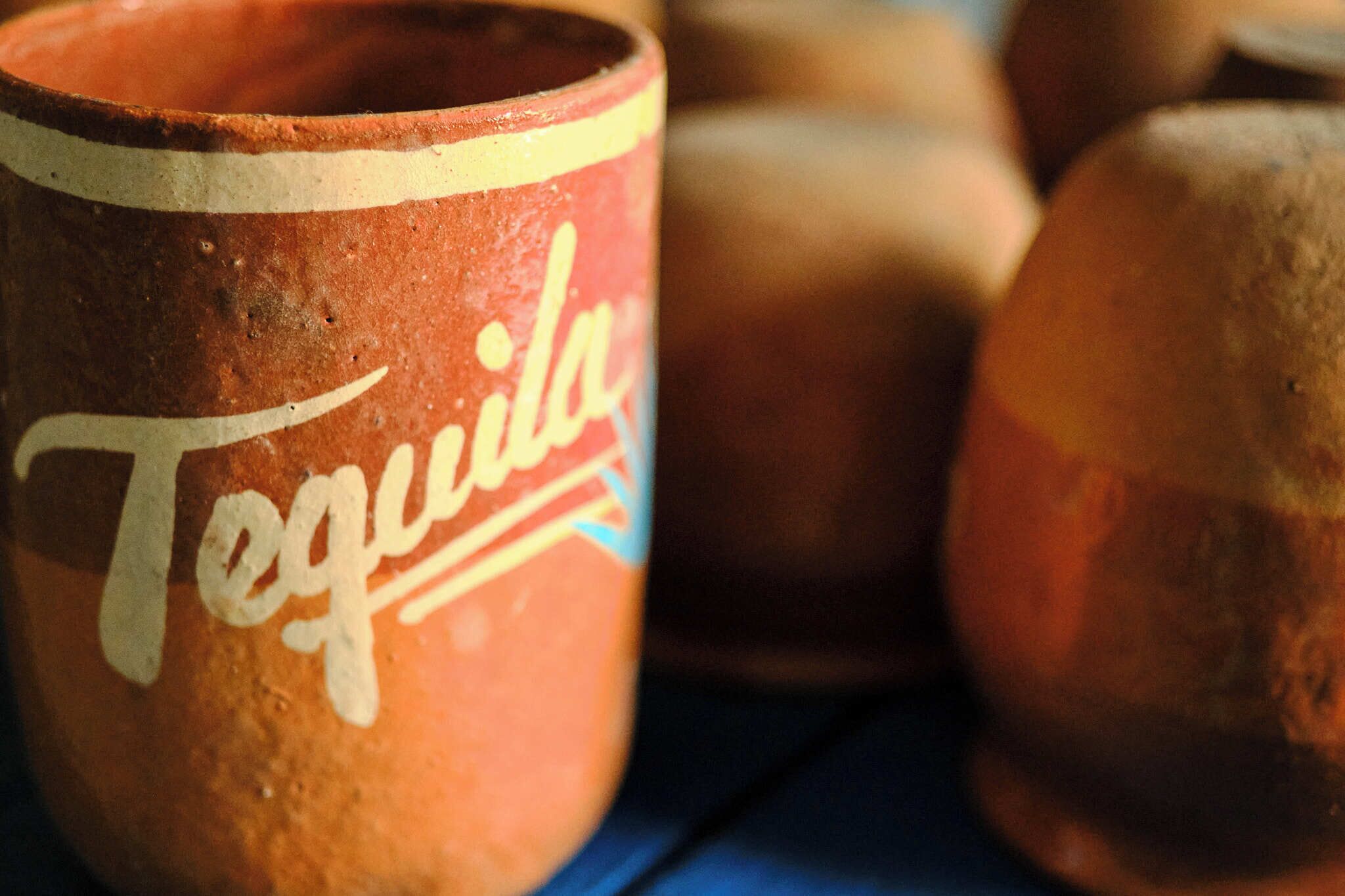 A close-up of a clay mug with the word "Tequila" written on it.