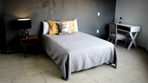 A bedroom with a bed, a desk, and a chair.