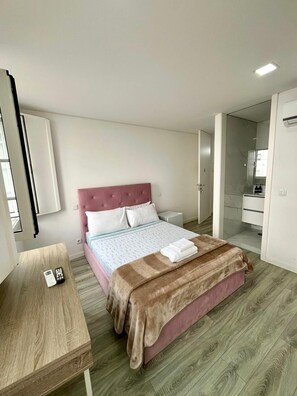 A bedroom with a bed, bedside table, and a bathroom visible through an open door. - Casa Augusta 6 (Braga)