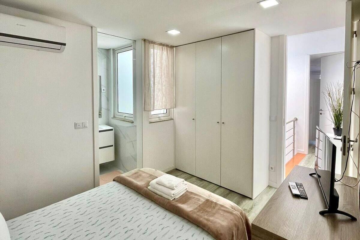 A bedroom with a bed, a desk, a wardrobe, and a mirror.