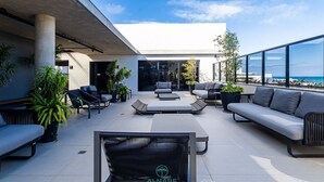 A modern outdoor patio with seating, planters, and a view of the sea. - Flat Way Style - By Almare (João Pessoa)