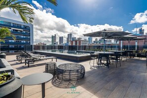 Terraza en la azotea con mobiliario exterior, piscina y vistas al horizonte de la ciudad.