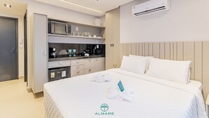A hotel room with a bed, a kitchenette, and an air conditioning unit. - Flat Way Style - By Almare (João Pessoa)