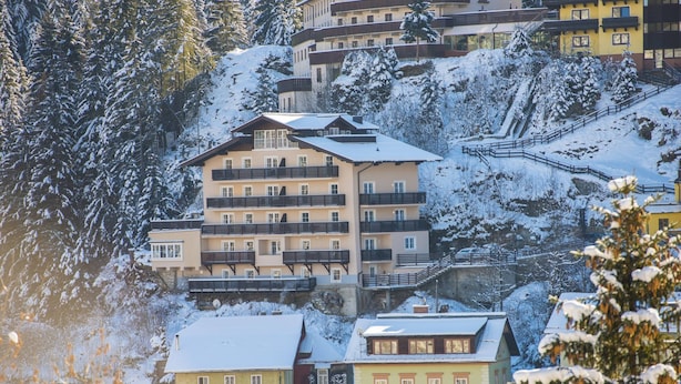 A multi-story building with balconies, surrounded by snow-covered trees and buildings. - Apartment in Bad Gastein Near Ski Slopes (Bad Gastein)