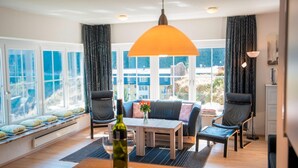 A modern living room with a large window, a sofa, two chairs, a wooden table, and a hanging lamp. - Apartment in Bad Gastein Near Ski Slopes (Bad Gastein)