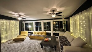 A cozy living room with a sofa, armchairs, a coffee table, and a ceiling fan. - Your Cozy Getaway with Sunroom & Gaming Room (Streamwood)