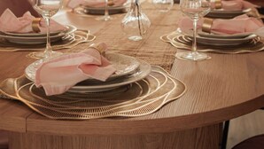 A round dining table set with plates, glasses, and a vase of flowers. - Your Cozy Getaway with Sunroom & Gaming Room (Streamwood)