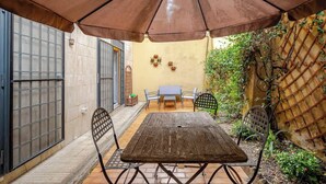 A patio with a wooden table and chairs, a large umbrella, and a small table with chairs. - Appartamento con terrazza vicino S.Pietro (Rome)