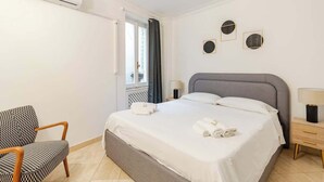 Une chambre d’hôtel équipée d’un lit, d’une chaise, d’une table de chevet et d’un climatiseur fixé au mur.