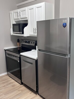 A kitchen with stainless steel appliances, including a refrigerator, oven, and microwave, with white cabinetry above. - The Grand Carriage Townhouse (Eau Claire)
