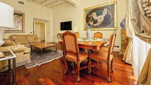 A well-furnished living room with a wooden coffee table, a sofa, and a dining area with a table and chairs. - Magnifica residenza a Campo de' Fiori (Rome)