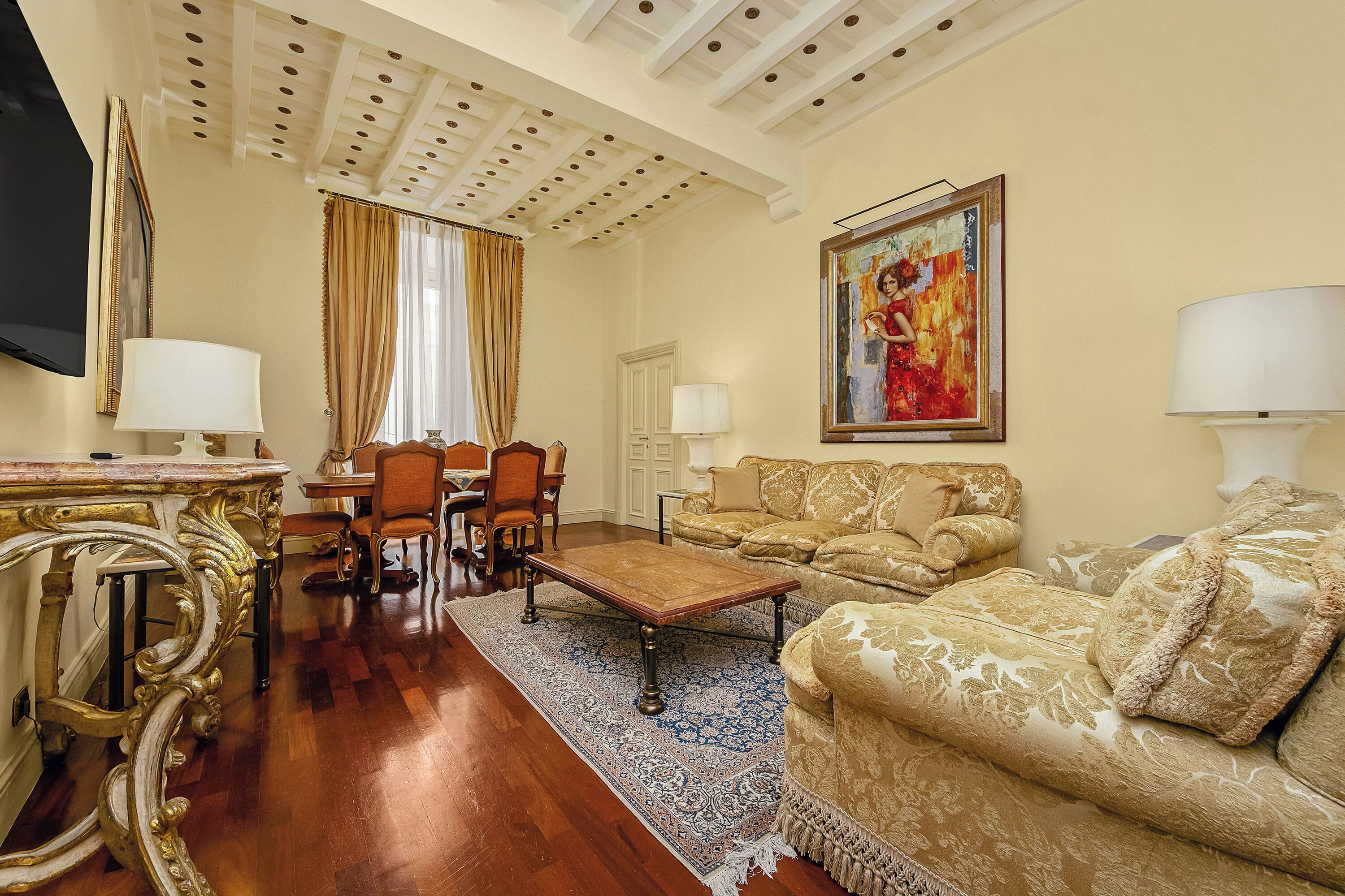 A living room with a wooden coffee table, a sofa, a dining table with chairs, and a television.