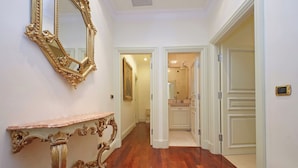 A hallway with polished wooden floors, a marble console table, and a large ornate mirror. - Magnifica residenza a Campo de' Fiori (Rome)
