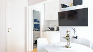 A modern living room with a white sofa, a round coffee table, and a mounted flat-screen TV. - Iadra apartment in city center (Zadar)
