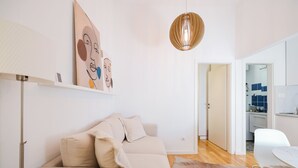 A modern living room with a beige sofa, a white table, and a hanging pendant light. - Iadra apartment in city center (Zadar)