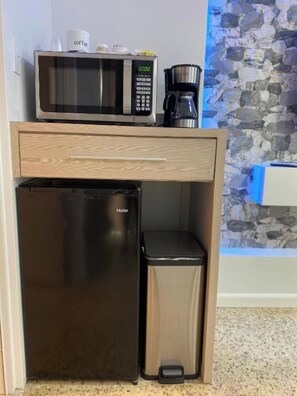 Compact kitchenette with microwave, coffee maker, and refrigerator.