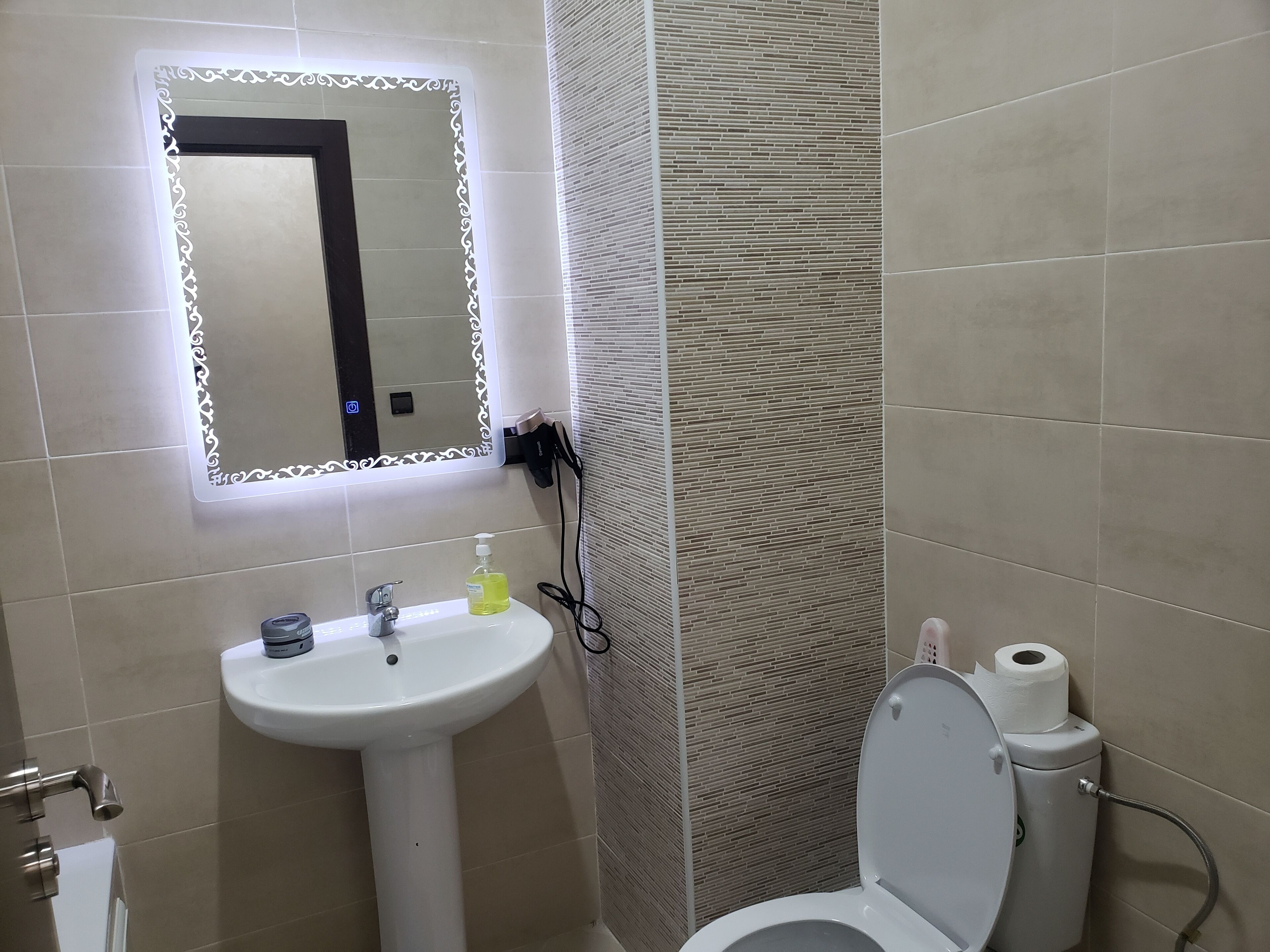 Une salle de bain avec un lavabo blanc, un miroir et des toilettes.