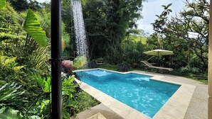 A pool with a waterfall feature surrounded by lush greenery. - Nutabe House, Girardota 40 min from Medellín! Ideal house for families and friends  (Girardota)