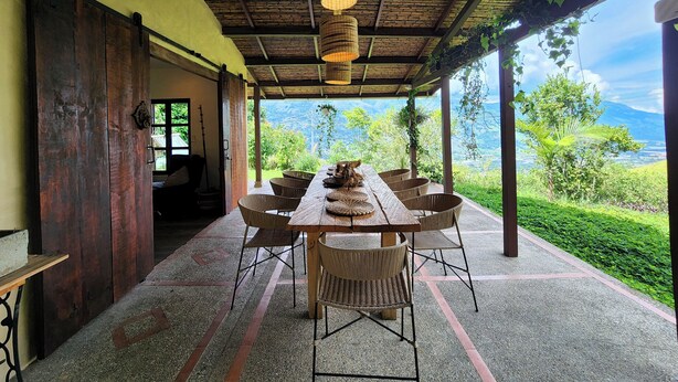 A covered outdoor dining area with a table and chairs, a hanging light fixture, and a view of a mountainous landscape. - Nutabe House, Girardota 40 min from Medellín! Ideal house for families and friends  (Girardota)