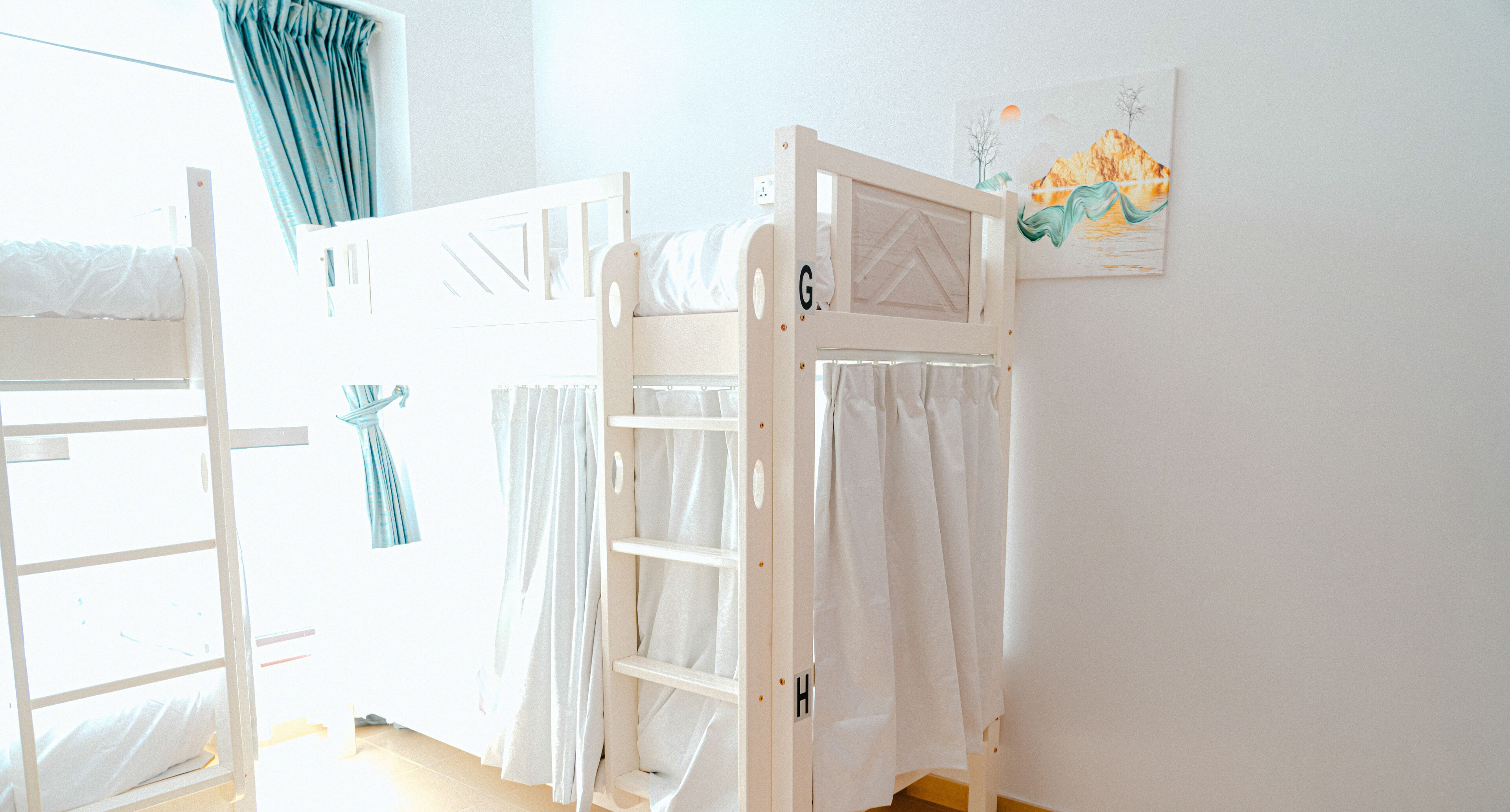 A child's room with bunk beds, a white wall, and a painting.