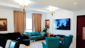 Ein Wohnzimmer mit einem großen Flachbildfernseher an der Wand, einem Sofa und zwei Sesseln.