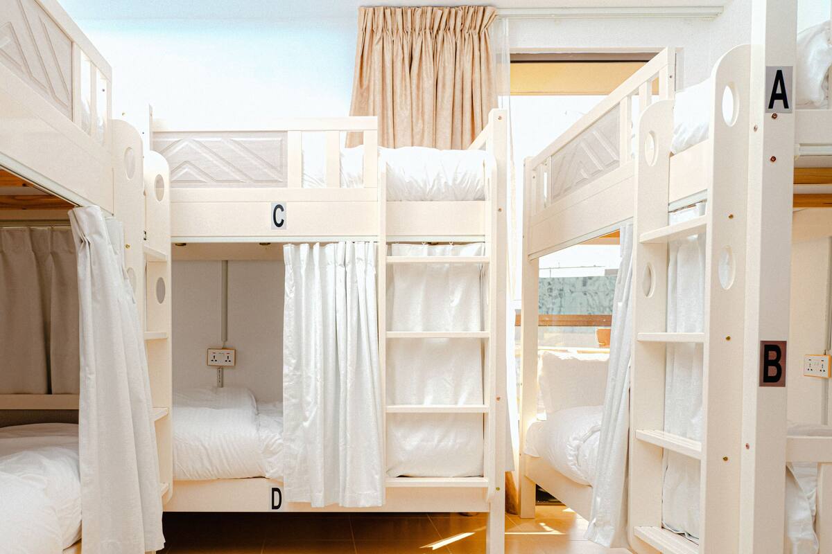 A bunk room with three levels of beds, labeled A, B, and C, and a small shelf unit.