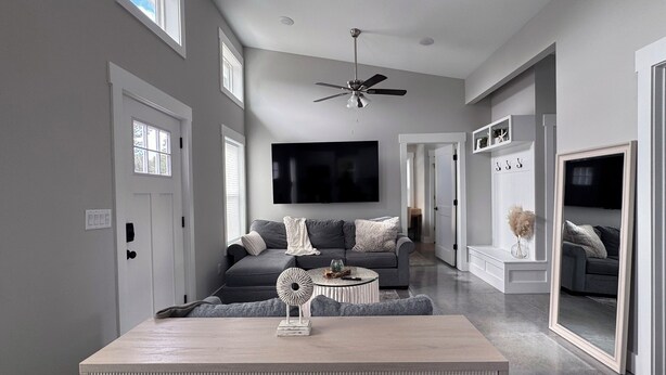 A modern living room with a grey sofa, a wooden coffee table, and a ceiling fan.