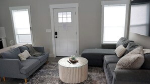 A living room with two grey sofas, a round coffee table, and a door with a window.