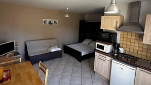 A compact living space with a kitchenette, a sofa, a dining table, and a bed. - Résidence Les Roussets (Jonzac)