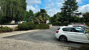 A white car parked on a gravel road with trees and a clear sky in the background. - Résidence Les Roussets (Jonzac)
