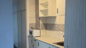 A modern kitchen with white cabinets, a microwave, and a sink. - Cozy apartment in Gava Mar. (Gavà)