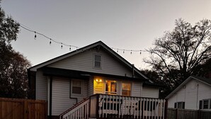 A two-story house with a covered porch, a wooden deck, and a fenced backyard. - Cute home with fenced backyard, firepit & swings. Near downtown. Pet-friendly! (Kannapolis)