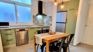 A compact kitchen with a dining area, featuring a built-in oven, stainless steel dishwasher, and a refrigerator. - Newly renovated penthouse in the historic center of Almeria. (Almería)
