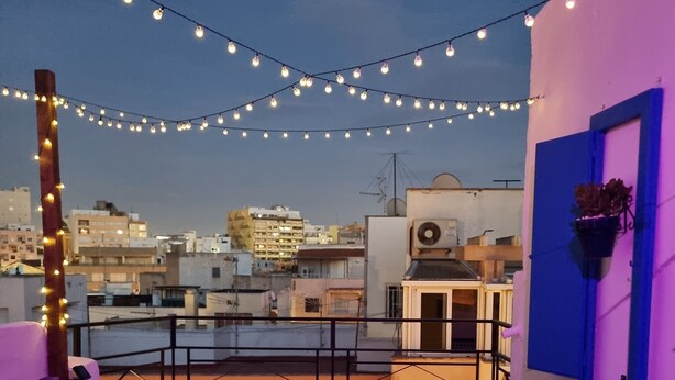 A rooftop terrace with string lights, wicker furniture, and a view of the cityscape. - Newly renovated penthouse in the historic center of Almeria. (Almería)