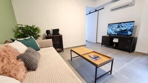 A modern living room with a sofa, coffee table, TV, and a plant. - Newly renovated penthouse in the historic center of Almeria. (Almería)