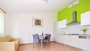 Eine moderne Küche mit weißen Schränken, einer grünen Akzentwand und einem Essbereich mit Tisch und Stühlen.