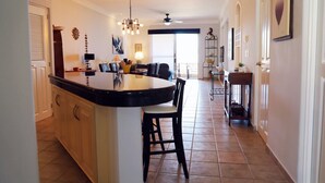 Un'ampia cucina con isola centrale, un'area pranzo con tavolo e sedie, e vista su un balcone.