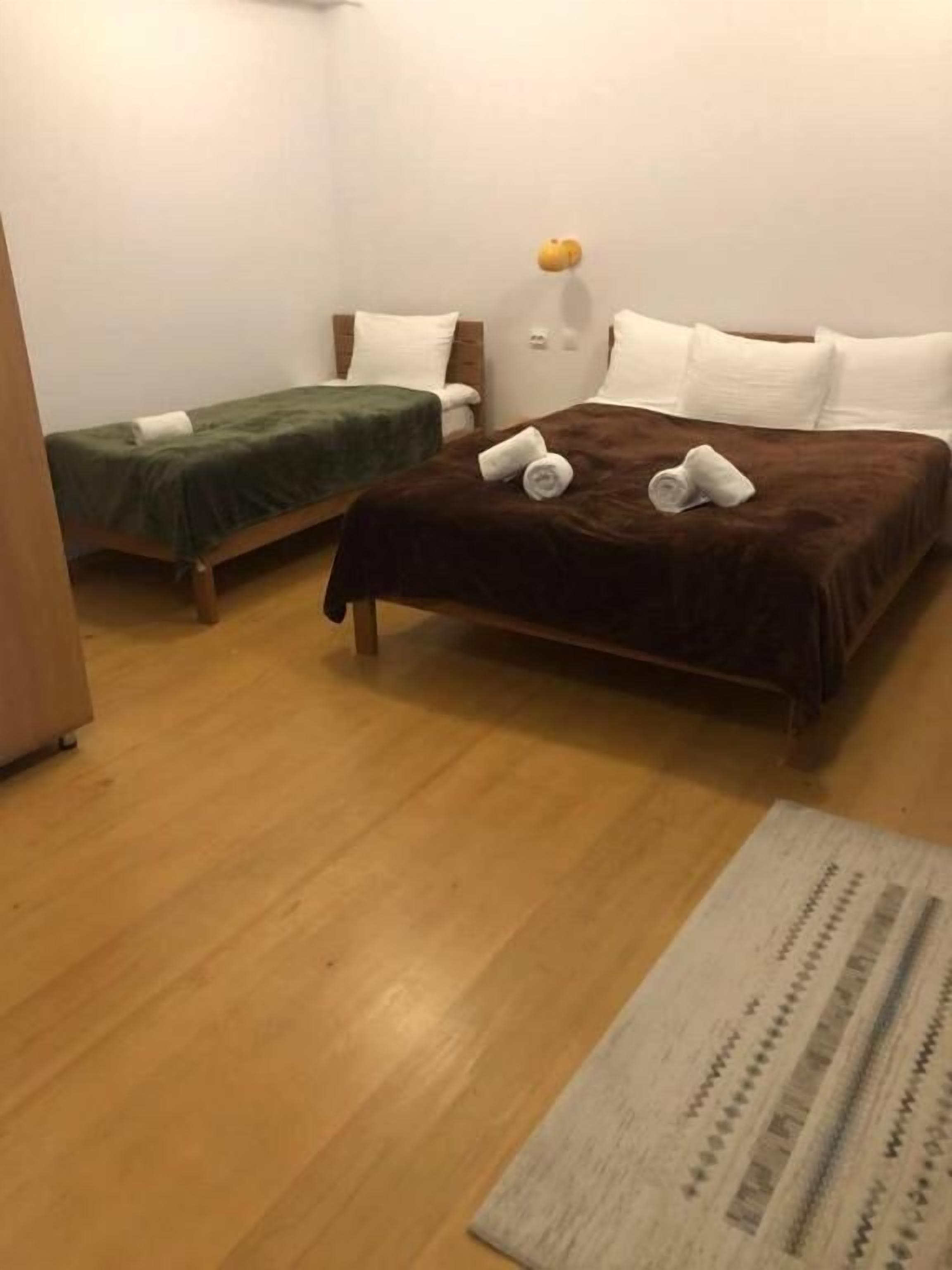 A hotel room with two beds, a wooden floor, and a small rug.