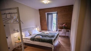 A bedroom with a bed, a bedside table, a chair, a window with curtains, and a wooden wall. - latour Mestia (Mestia)