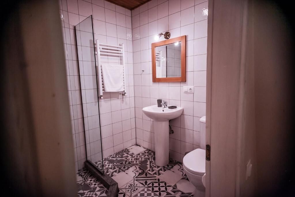 Pieni kylpyhuone, jossa on valkoinen pesuallas, peili ja wc-istuin.
