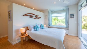 Una camera da letto con un letto, lampade sui comodini, una finestra con tende e un addobbo appeso al muro.