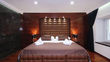 A modern hotel room with a large bed, wooden headboard, and two bedside tables with lamps.