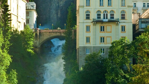 A multi-story building with a sign reading "Apartments Sponfeldner" near a bridge over a river. - Apartment in Bad Gastein Near Ski Lifts (Bad Gastein)