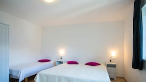 A hotel room with two single beds, each with a white bedspread and a purple pillow. There are bedside tables with lamps and a window with dark curtains. - Apartment in Salzburg Near Ski-lift (Bad Gastein)